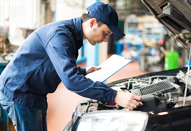 Mechanic inspecting car engine clipboard