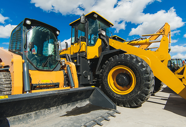 Yellow construction loaders under sky